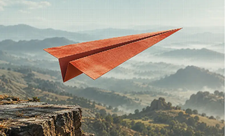 A terracotta paper airplane taking flight over a mountain valley